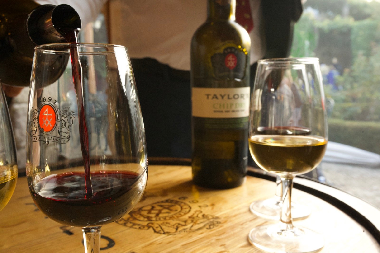 Glass of port being poured beside a bottle and a glass of white port