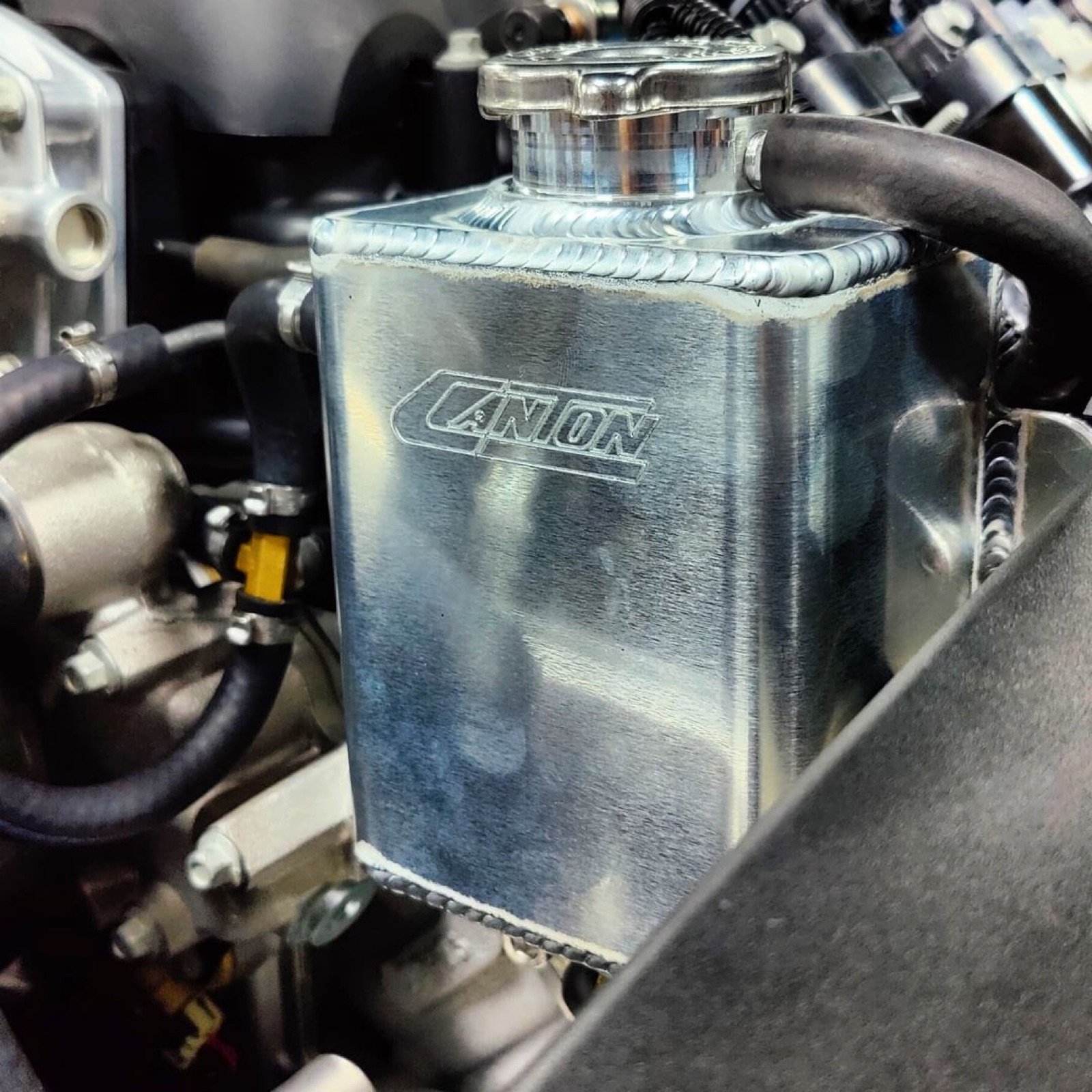 Polished aluminum catch can in the engine bay