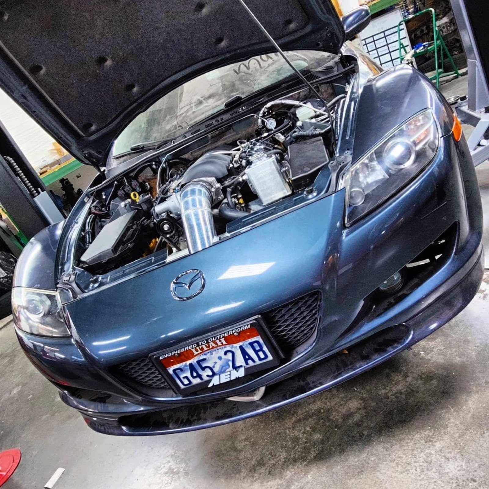Front three-quarter of a Mazda RX8 with the hood open showing the swap